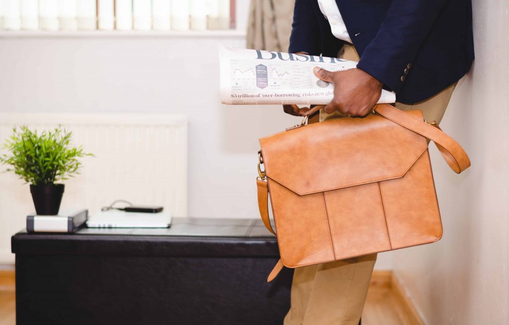 A businessman carrying a suitcase and a newspaper